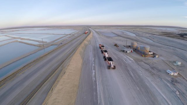 Aerial shot of a large truck empty passing in front of another one full of salt in Guerrero Negro, Ojo de Liebre lagoon, Biosphere Reserve of El Vizcaino, Baja California Sur.