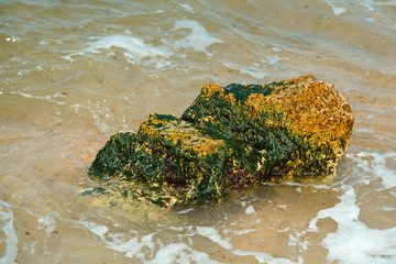 The wreckage of rocks near the sea shore in the water with splashes.