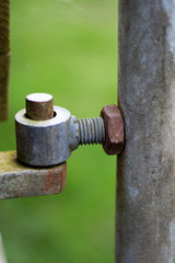 Rusty pivot hinge on farm gate providing access to farmland field in rural Hampshire with shallow depth of field