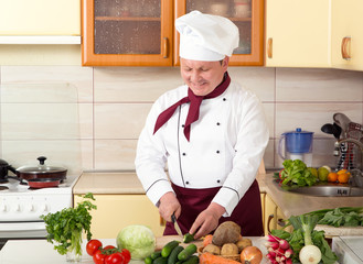 Mature male cook prepared vegetable salad in the kitchen. Man chef knows the cooking recipes.