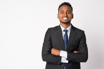 Happy young handsome African businessman smiling with arms crossed