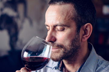 Man tasting a glass of red wine. Selective focus.