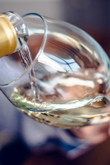 Pouring white wine in glass. Selective focus.