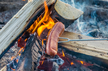 cuisson d'une saucisse au barbecue dans la nature