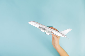 jet airplane model in human hand on blue background. concept of a plane taking off and flying to...