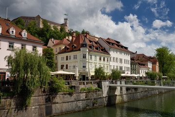 Fototapeta na wymiar Renovated historic buildings Cankar Quay embankment of the Ljubljanica river canal at Fish Bridge and Castle Hill of Ljubjlana Slovenia