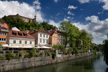 Fototapeta na wymiar Bright pastel colors of renovated historic buildings Cankar Quay embankment of the Ljubljanica river canal and Castle Hill of Ljubjlana Slovenia