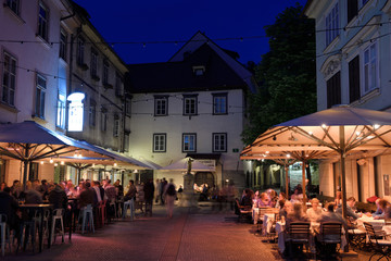 Nightlife outdoor restaurant cafes in Cobblestone Courtyard Ribji or Fish Square from Cankar Quay to Town Square in Old Town Ljubljana Slovenia