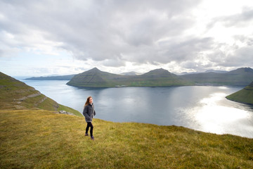 Fototapeta na wymiar Young woman hiking near the town of Klaksvik, Bordoy, Faroe Islands