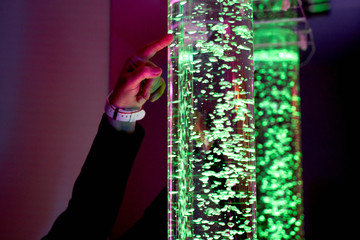 therapy sensory stimulating multi sensory room, woman interacting with colored lights bubble tube lamp during therapy session