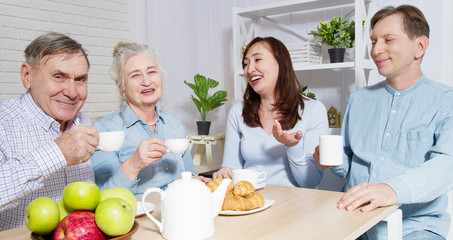 Happy family tea time at nursing home for elderly. Parents with children have fun talk communication and leisure. Senior couple and relatives. Visit old mother and father. Parenting care concept