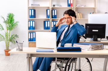 Male employee in wheelchair working at the office 