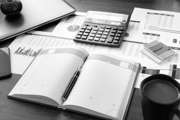 Open leather notebook, laptop, cup of coffee, calculator, graphs, data and drawings on the working office desk. Business and Finance.