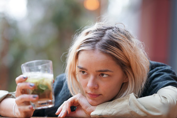 Sad looking woman holding a drink on the table