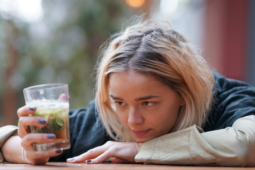 Sad looking woman holding a drink on the table