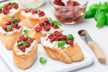 Bruschetta with sun dried tomato, feta and philadelphia cheese and basil on ceramic plate, horizontal