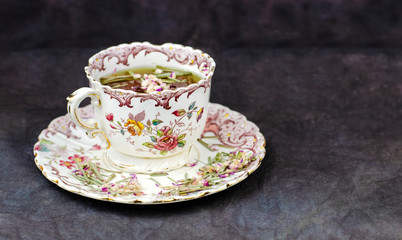 Beautiful vintage tea cup with with a herbal tea on dark background
