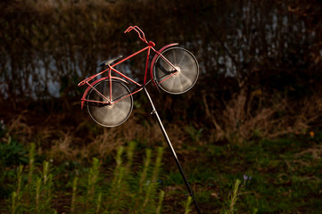 Windrad in Form eines Fahrrades bei Gewitterlicht