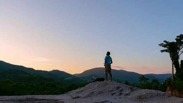 4K Time Lapse of Young man controls drone on high mountain with Beautiful sky sunset or sunrise time 