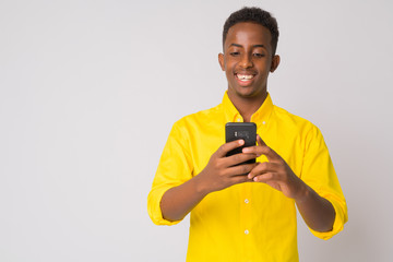 Happy young African businessman with yellow shirt using phone