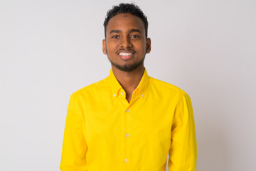 Happy young handsome African businessman with yellow shirt smiling