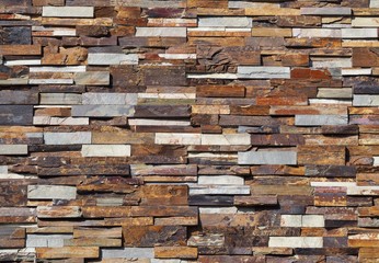 Stone cladding wall made of  striped stacked slabs of natural colored rocks. Panels for exterior .