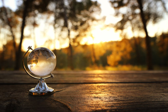 small crystal globe in front of sunset. travel and global issues concept