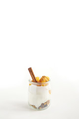 Jars of greek yogurt with granola, cinnamon and canned apricots on white background, copy space, vertical oriented
