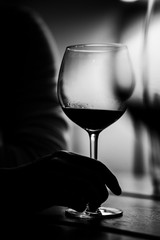 Hand holding glass of wine in black and white