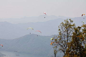 Flying on a paraglider. Beautiful view with mountains and colorful paragliders. Extreme vacation...