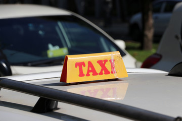 Taxi light sign or cab sign in yellow color with red text on the car roof at the street blurred background