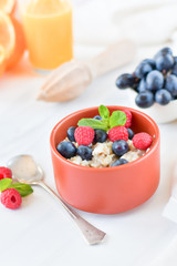 oatmeal with organic blueberries and raspberries, fresh orange juice and grapes. light background, selective focus and copy space, Breakfast concept. diet, healthy food