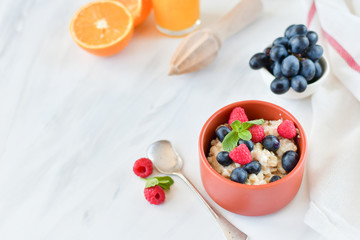 oatmeal with organic blueberries and raspberries, fresh orange juice and grapes. light background, selective focus and copy space, Breakfast concept. diet, healthy food
