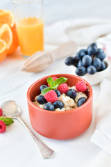 oatmeal with organic blueberries and raspberries, fresh orange juice and grapes. light background, selective focus and copy space, Breakfast concept. diet, healthy food