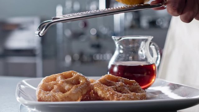 Orange zest over fritters multiple passes, slow motion, side view