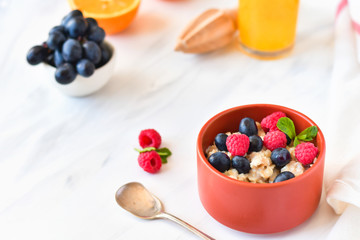 oatmeal with organic blueberries and raspberries, fresh orange juice and grapes. light background, selective focus and copy space, Breakfast concept. diet, healthy food