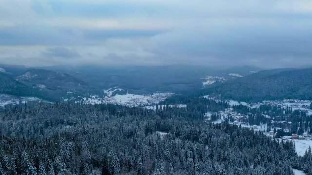 Drone time lapse, Winter sports resort Borsec in Romania, aerial view of frozen forest and resort with some clouds on the sky.