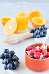 oatmeal with organic blueberries and raspberries, fresh orange juice and grapes. light background, selective focus and copy space, Breakfast concept. diet, healthy food