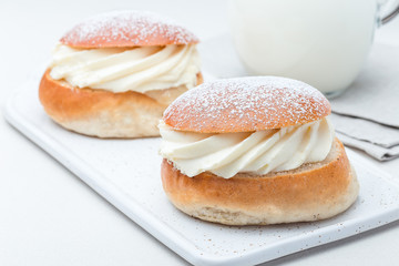 Traditional swedish dessert Semla, also called Shrove bun, with almond paste and whipped cream filling, served with milk, horizontal