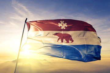 Komi-Permyak Okrug of Russia flag waving on the top sunrise mist fog