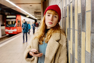 junge Frau wartet in einer U-Bahn Station auf den Zug