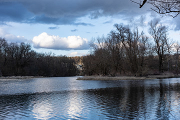 Weiss graue Wolken über ruhiger brauner Auenlandschaft, mit Verzweigung im alten Aare Flusslauf und silbernen Spiegelungen im gekrausten Wasser. Hintergrund, Konzept.