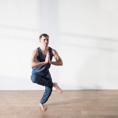 Fototapeta premium Young man doing yoga indoor. Workout Exercise Fitness Health Concept.