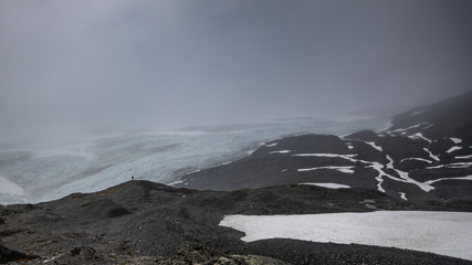 Lonely person in front of Exit glacier under the clouds 16:9