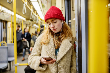 junge Frau, Teenager, Mädchen fährt mit ihrem Smartphone in der Hand U-Bahn