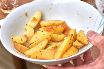 A hand holds a plate with remnants of hot idaho fried potatoes