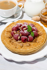 traditional sweet pancakes with fresh raspberries for breakfast on wooden table, vertical