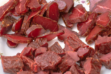 sliced cuts of meat, basturma, beef jerky, horse meat with spices on a plate, close-up