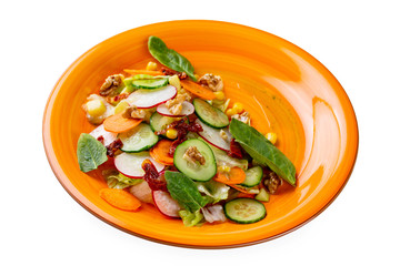Plate of fresh healthy vegetables salad with carrot, radish, basil, cucumber and nuts isolated at white background.