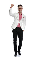 successful young elegant man celebrating with hand in the air